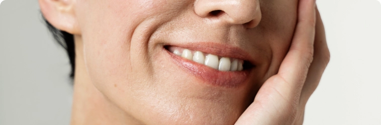 Mulher com a mão no rosto e sorrindo